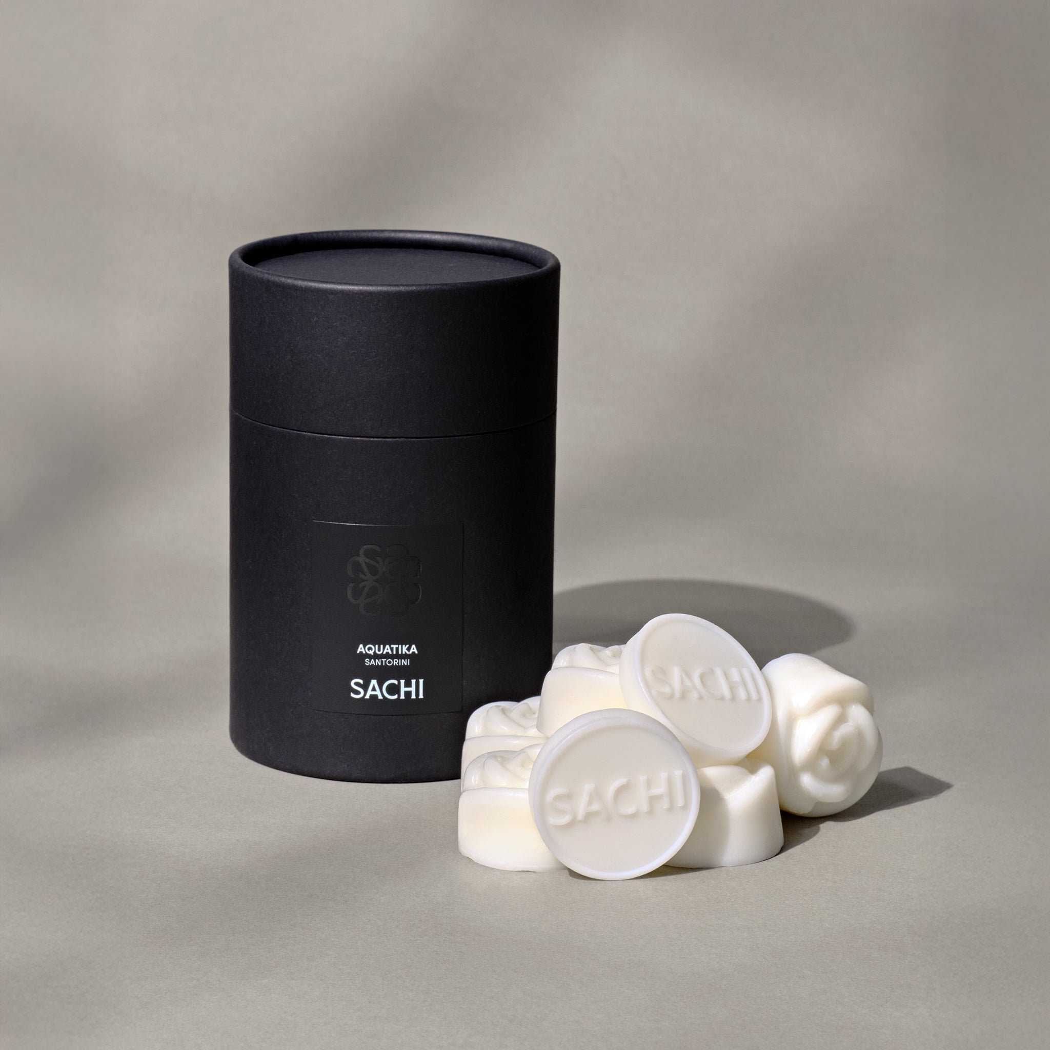 A black Sachi branded tubular gift box with ivory wax melts displayed on a neutral background.