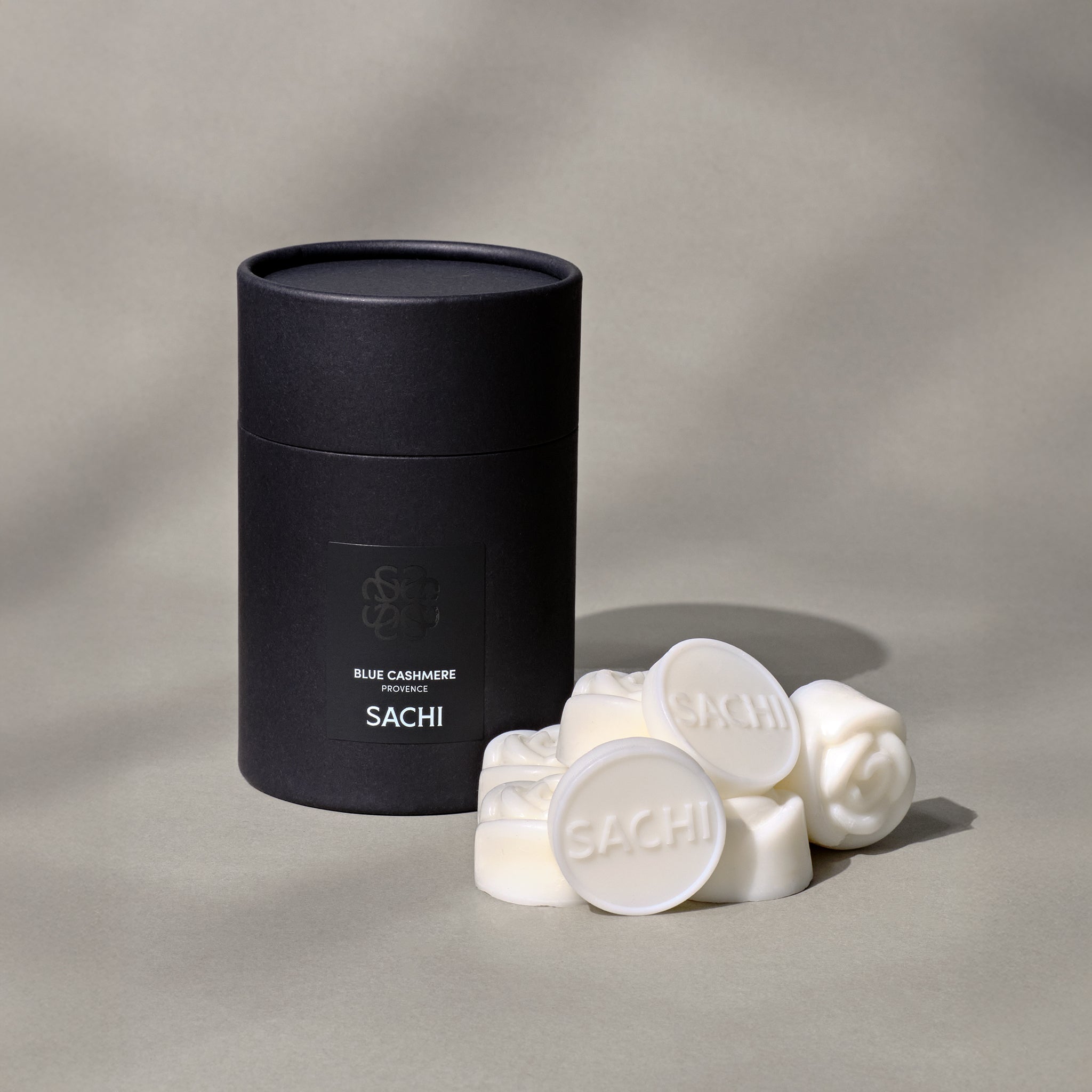 A black branded tube box with ivory wax melts on a neutral background