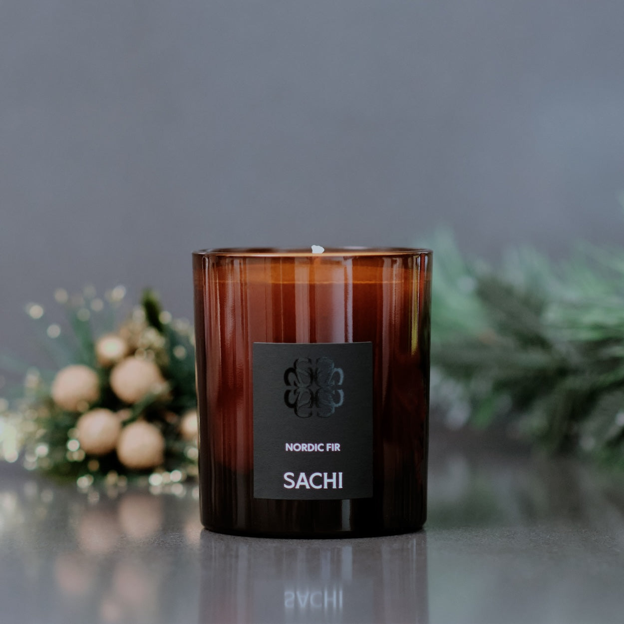Amber glass Christmas Tree scented candle with a label in a blurred decorative setting