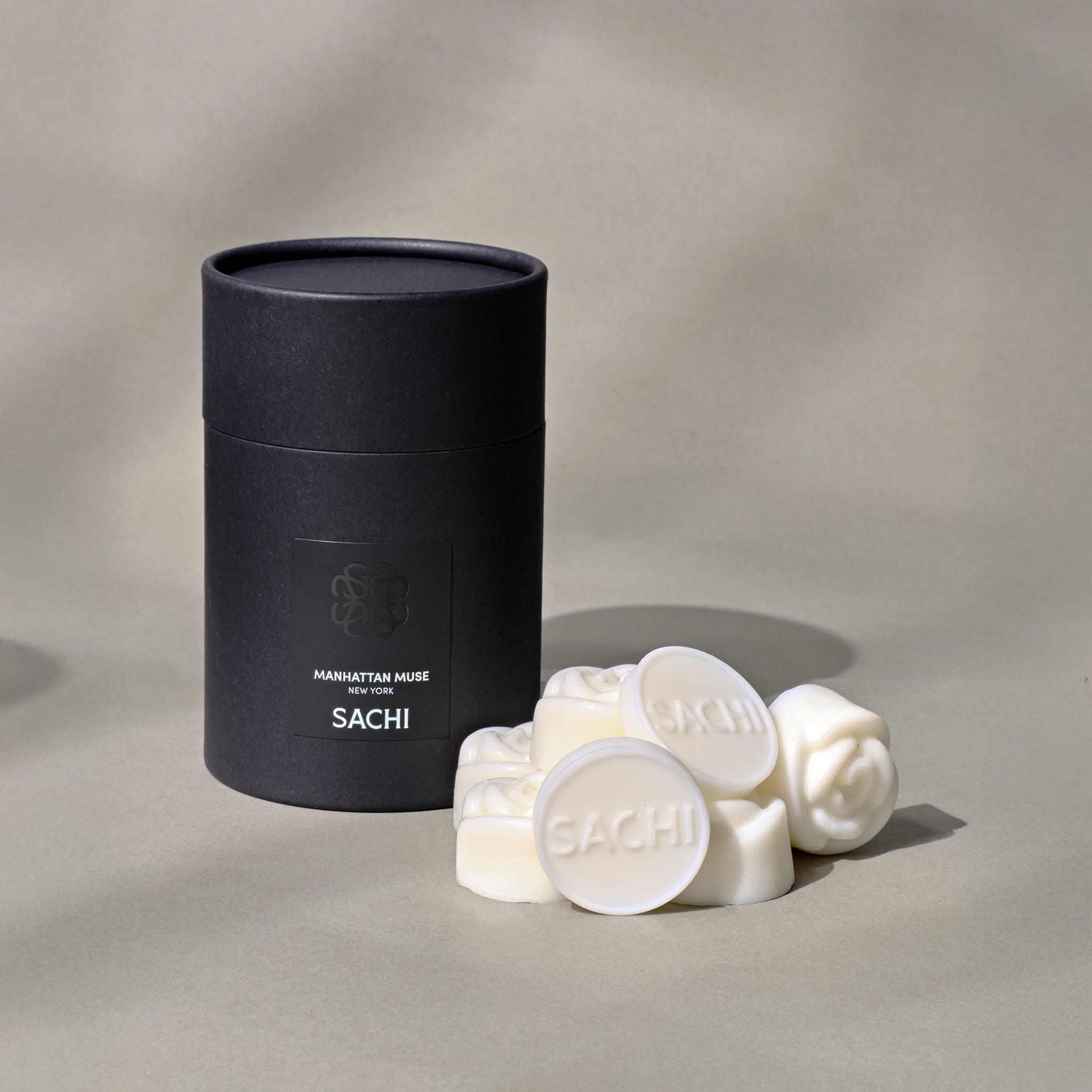 A black Sachi branded tubular gift box with ivory wax melts displayed on a neutral background.