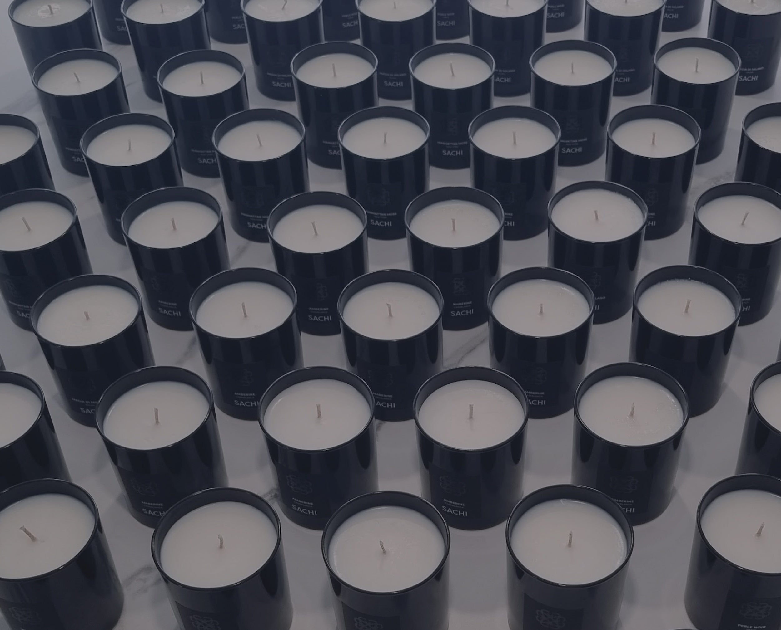Multiple rows of Sachi branded candle jars in black.