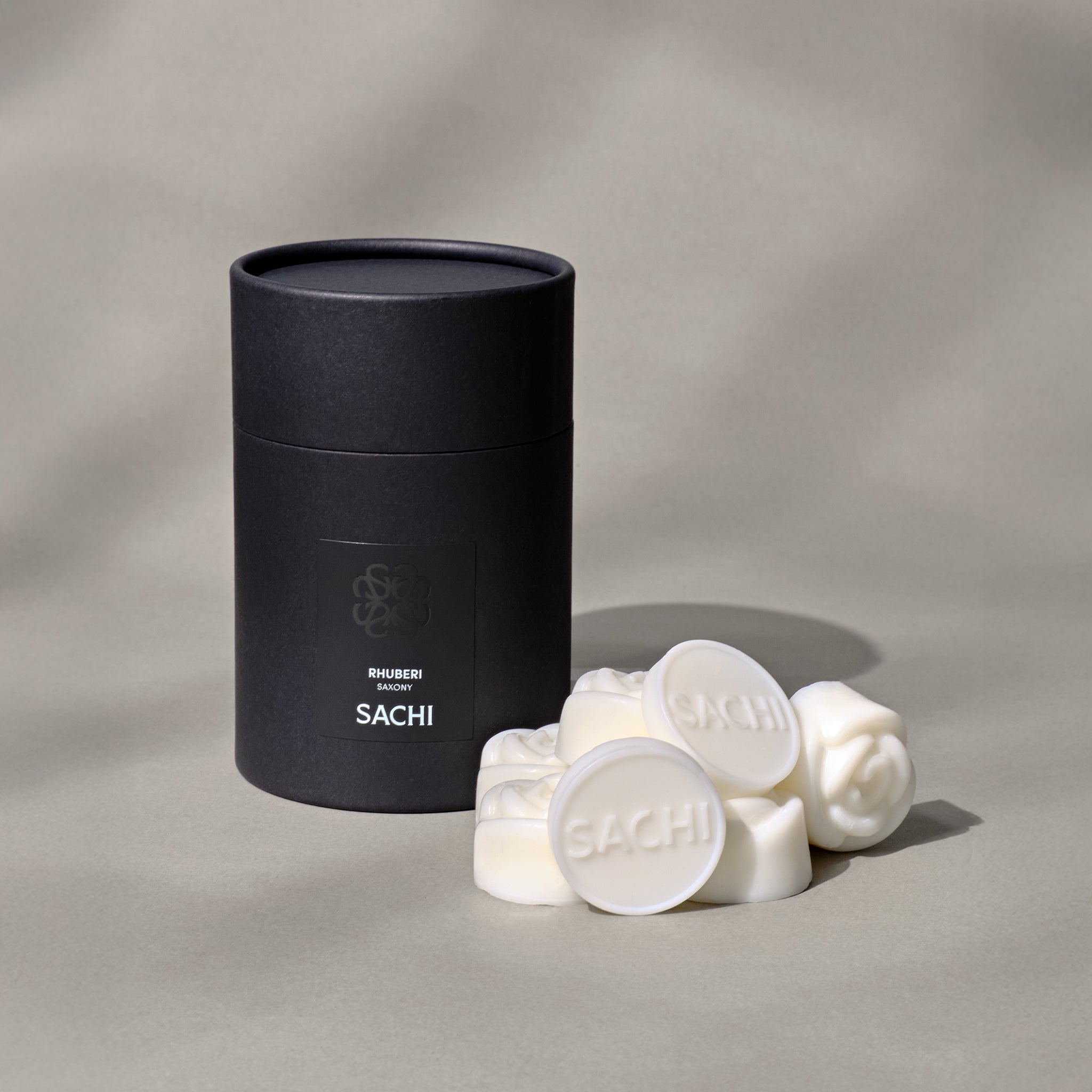 A black Sachi branded tubular gift box with ivory wax melts displayed on a neutral background.