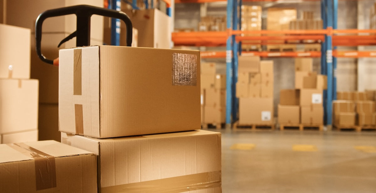 Cardboard boxes stacked in a warehouse with a forklift.