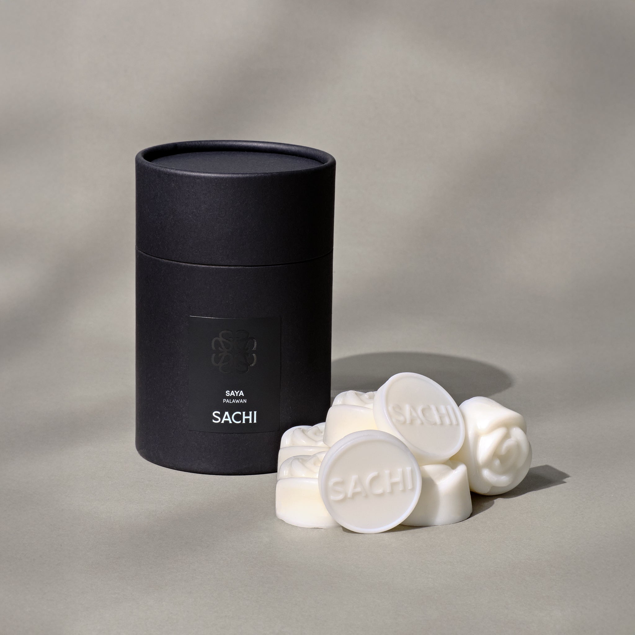 A black Sachi branded tubular gift box with ivory wax melts displayed on a neutral background.