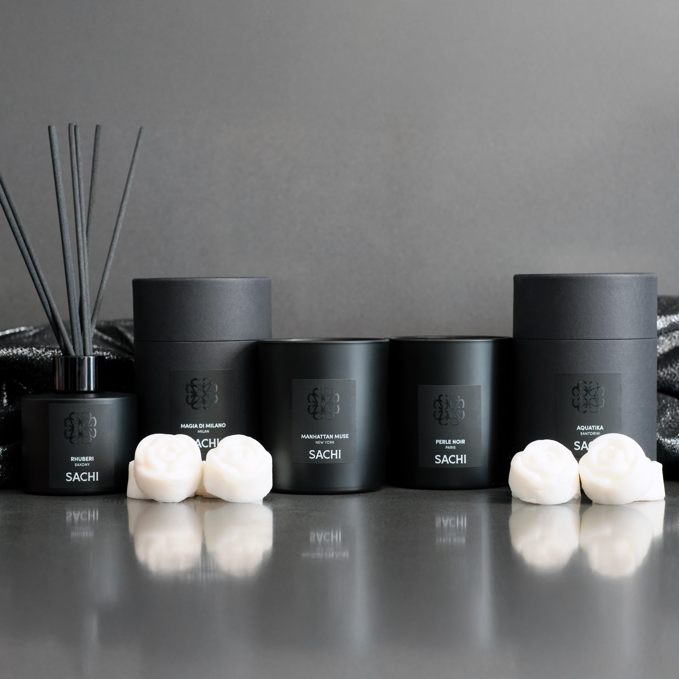 Black home fragrance products with Sachi branding on a grey surface