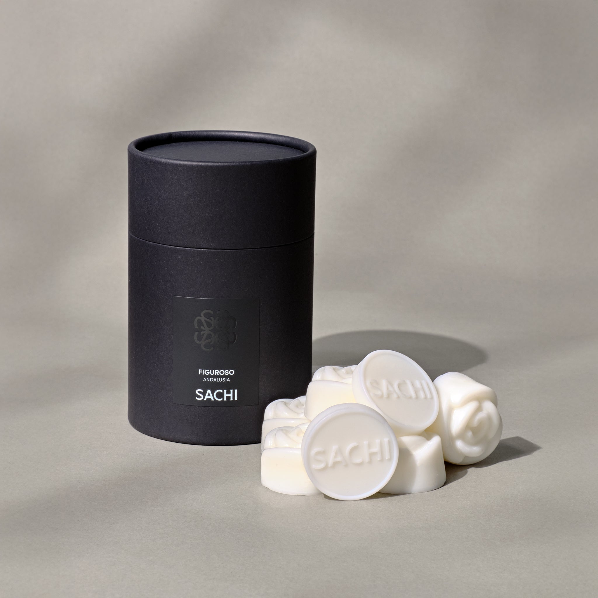 A black Sachi branded tubular gift box with ivory wax melts displayed on a neutral background.