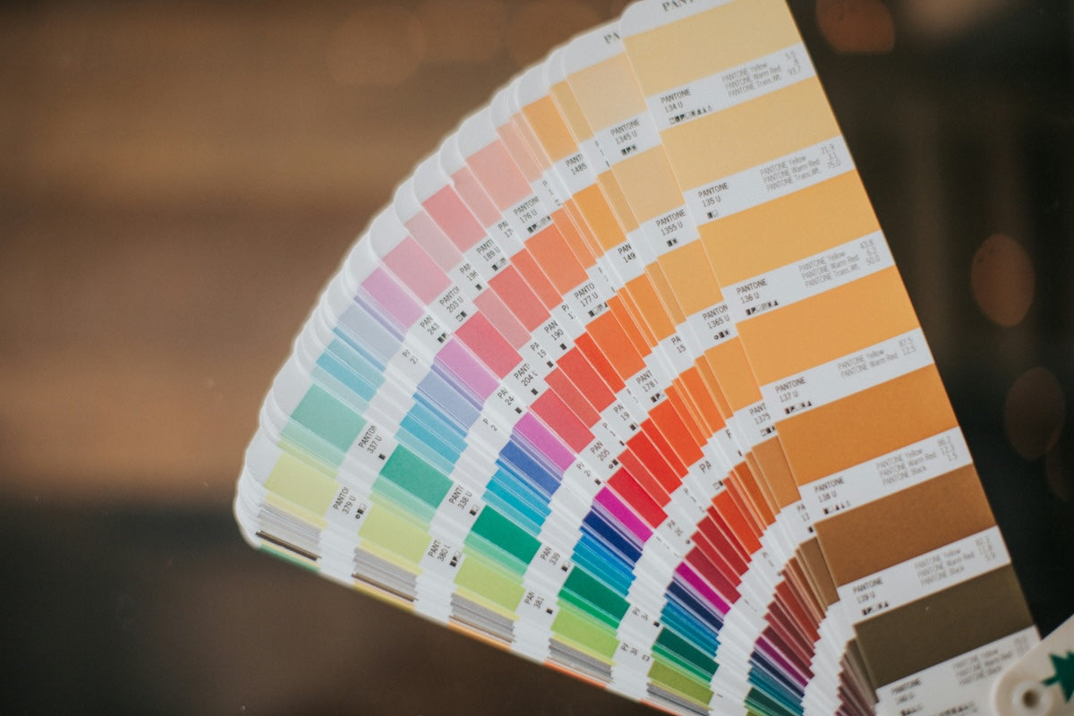 Pantone colour swatch chart held in hand with a blurred background