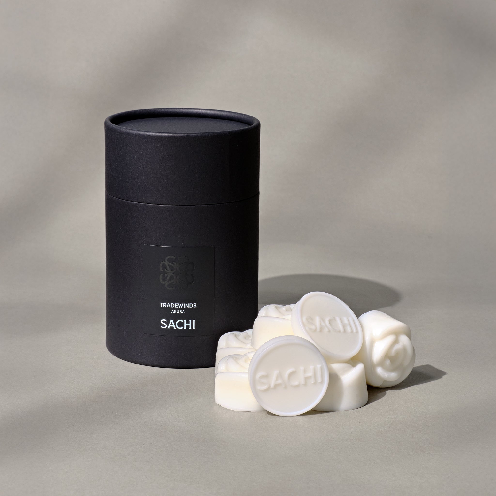 A black Sachi branded tubular gift box with ivory wax melts displayed on a neutral background.