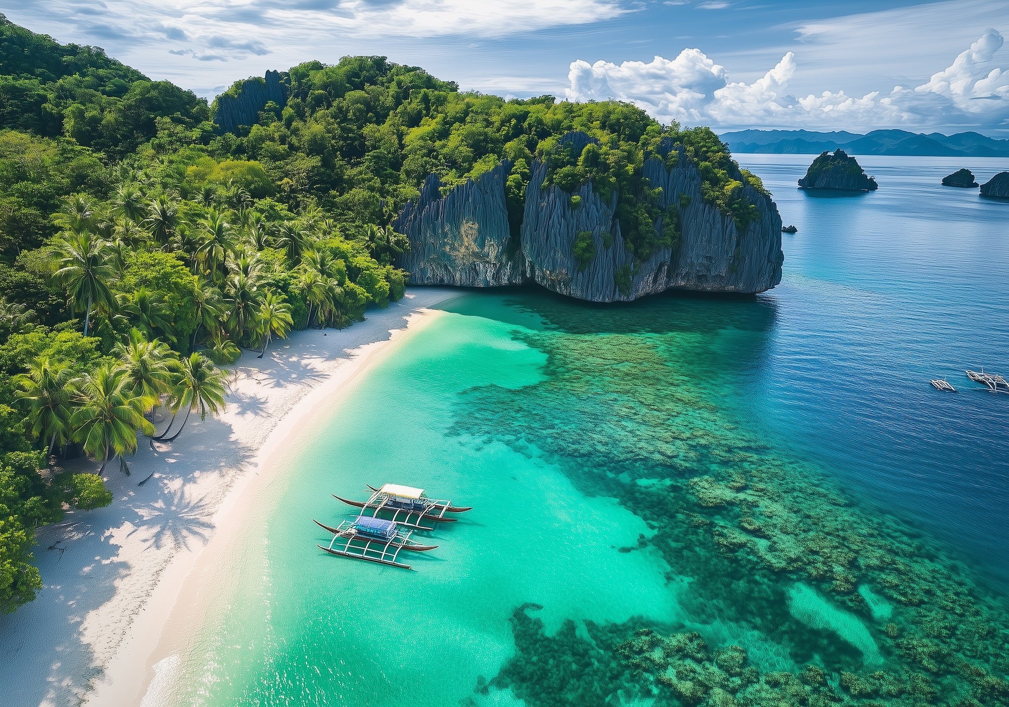 An aerial shot of islands in the Phillipines showing crystal clear waters, white sandy beach and palm trees.